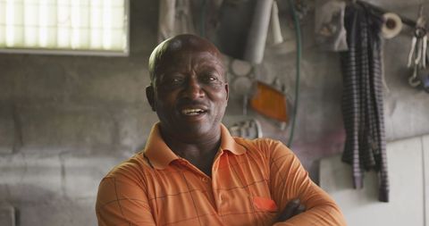 Confident African Man in Orange Shirt in Township Workshop - Download Free Stock Images Pikwizard.com