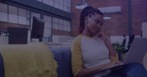 African American woman typing on laptop in modern coworking loft, focused remote work