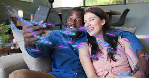 Couple taking selfie on sofa with neon motion streaks and cozy living room mood