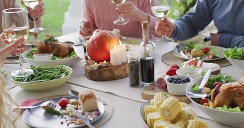 Friends clinking wine glasses around rustic outdoor fall table with candle centerpiece