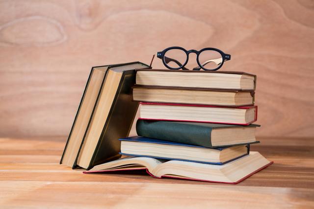Various books with spectacles on a wooden table