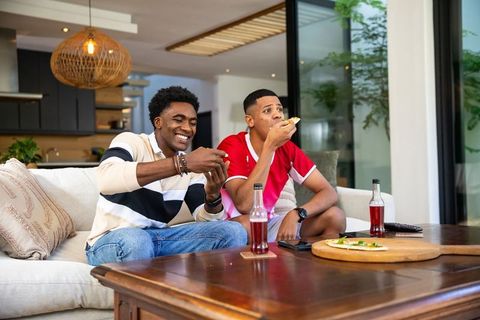 Friends Relaxing with Pizza and Gaming in Modern Living Room