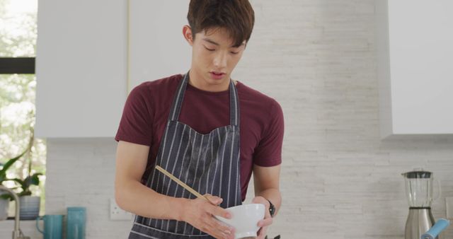 Young Man Cooking Holding Bowl and Chopsticks in Modern Kitchen - Download Free Stock Images Pikwizard.com