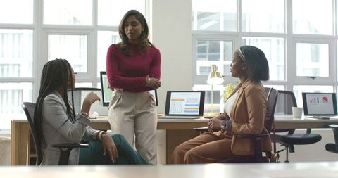 Diverse Women Collaborating and Leading Project Discussion in Modern Open-Plan Office