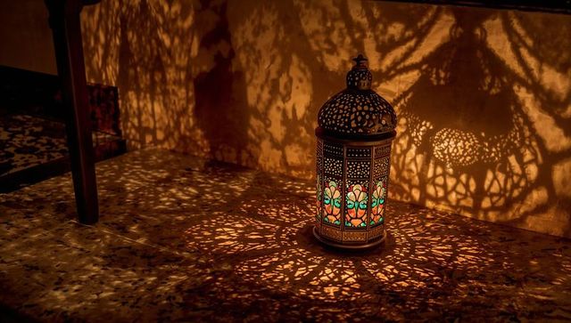 Ornate moroccan lantern casting filigree shadows on terrazzo floor with stained glass glow