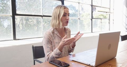Excited professional woman video conferencing at office desk