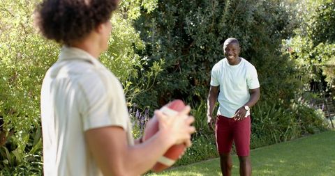Friends Enjoying Outdoor Football Game in Sunny Garden