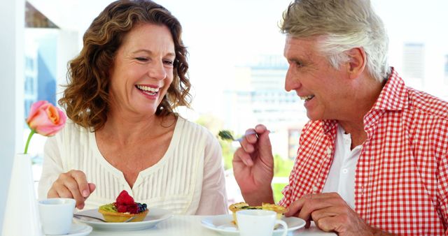 Senior couple smiling and enjoying desserts and coffee, fostering a joyful conversation outdoors. Ideal for promoting retirement lifestyle services, senior living communities, and marketing products geared towards older adults. This image suggests happiness, togetherness, and a fulfilling retiree lifestyle.