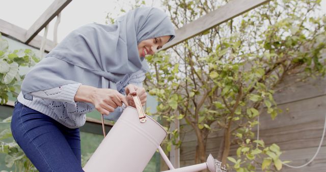 Woman in Hijab Smiling While Watering Plants in Greenhouse - Download Free Stock Images Pikwizard.com