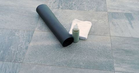 Yoga Mat with Water Bottle and Towel on Grey Stone Floor