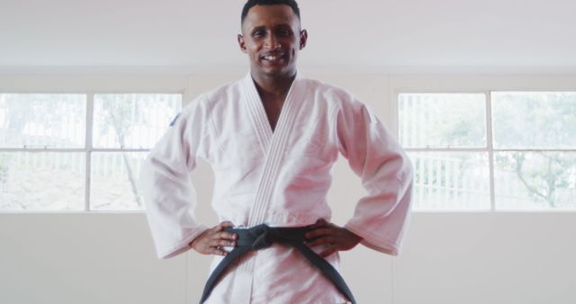 Smiling Martial Artist in White Gi with Black Belt Standing Confidently - Download Free Stock Images Pikwizard.com