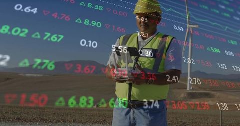 Engineer operating tablet at wind farm with data overlay
