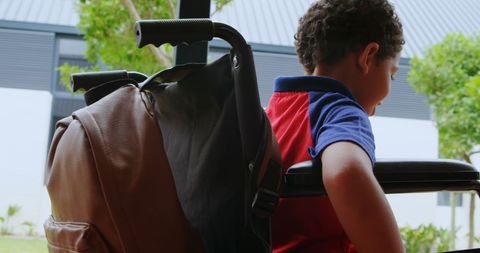 Schoolboy Moving Wheelchair in Corridor Side View