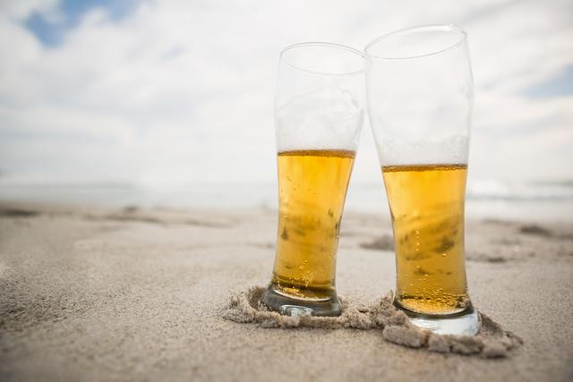 Two beer glasses kept on sand at tropical beach