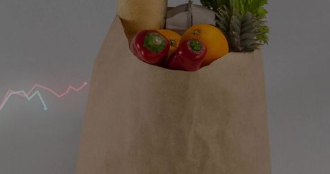 Kraft grocery bag overflowing with fresh produce, baguette and greens on neutral tabletop
