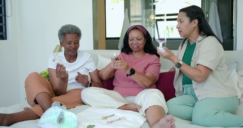 Mature women applying facial serums and testing led light therapy mask during self-care