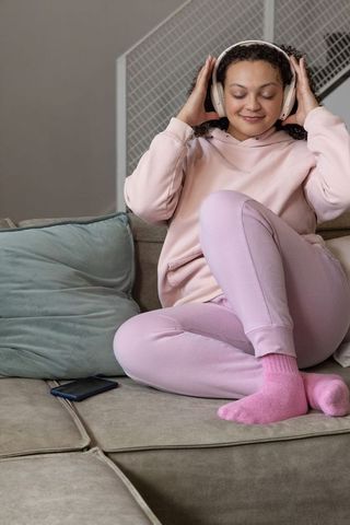 Listening to music on couch in pastel loungewear relaxing with headphones
