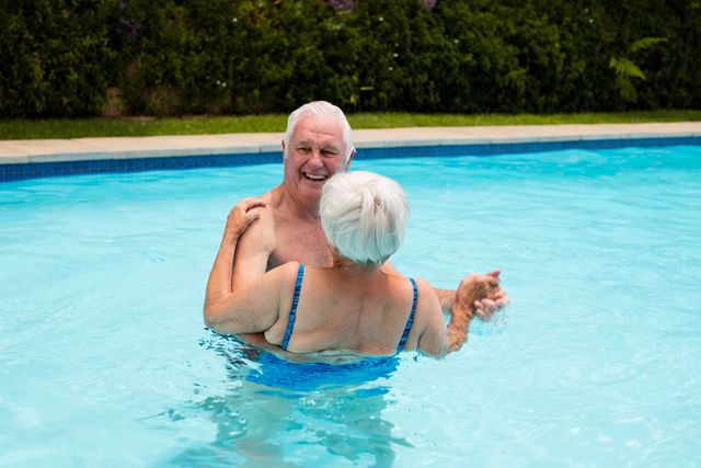 Senior couple enjoying a joyful moment dancing in a swimming pool. Perfect for illustrating active retirement, senior lifestyle, summer fun, and romantic moments in older age. Ideal for use in advertisements, brochures, and articles related to senior living, health, and wellness.