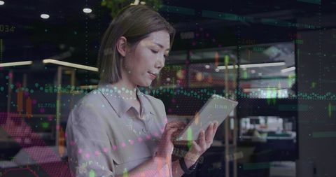 Asian Businesswoman Analyzing Data Charts on Tablet in Modern Office