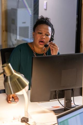 African american customer service agent speaking on headset while working at computer desk