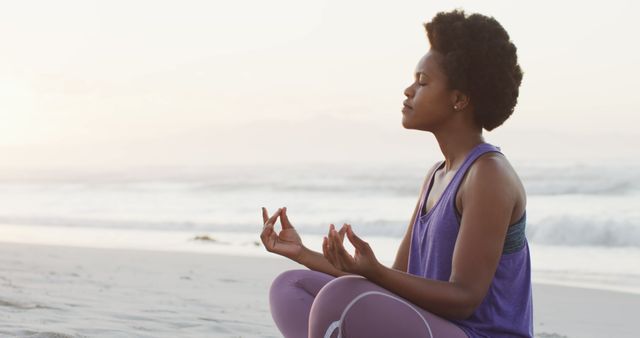 An individual is practicing meditation on a serene beach during sunrise, engaging in a yoga pose with closed eyes and a calm demeanor. This can be used for promoting wellness, fitness, mindfulness, and self-care practices. It also suits marketing materials for nature retreats, meditation apps, and fitness programs.
