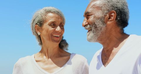 Joyful Senior Couple Enjoying Beach Day Under Blue Sky