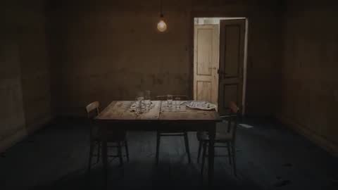 Rustic dining table soaking up light from ajar door in dim room with bare bulb