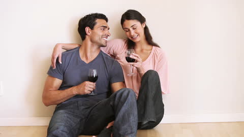 Couple Relaxing Toasting with Red Wine in Empty Room
