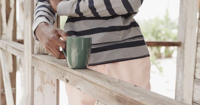 Person Holding Coffee Mug by Rustic Wooden Fence in Striped Shirt - Download Free Stock Images Pikwizard.com