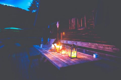 Lantern-lit rustic cabin deck table at dusk with warm glow for cozy outdoor evenings