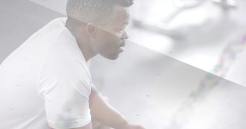 Man catching breath after intense battle rope workout white shirt gym high-key soft-focus
