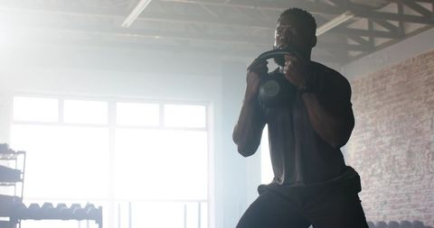Man performing kettlebell squats in industrial gym setting