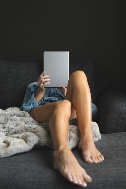 Front view of woman using digital tablet while relaxing on sofa in a comfortable home