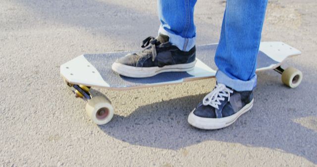 Close-up of person skateboarding on asphalt in blue jeans and black sneakers - Download Free Stock Images Pikwizard.com