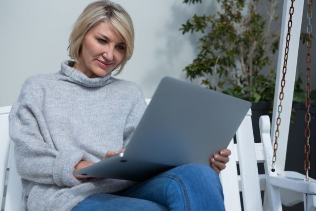 Beautiful woman using laptop in porch on a sunny day