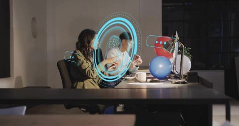Coworkers collaborating with blue holographic interface at office desk during celebration