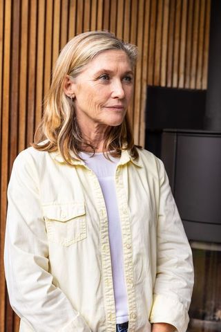 Senior woman gazing besides minimalist wooden wall in elegant room