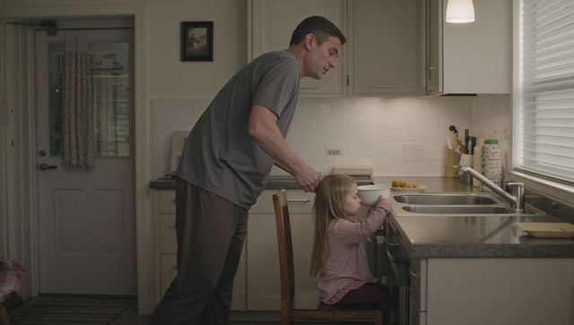 Dad helping young daughter reach bowl at kitchen counter cozy family breakfast moment