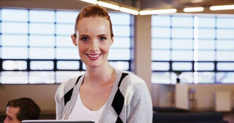 Smiling caucasian woman holding tablet in modern office