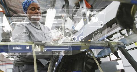 Female technician inspecting motor using augmented reality console in industrial plant