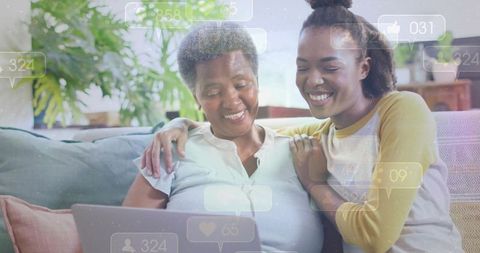 Mother daughter sharing laptop smiling on couch with social media icons and cozy home bonding