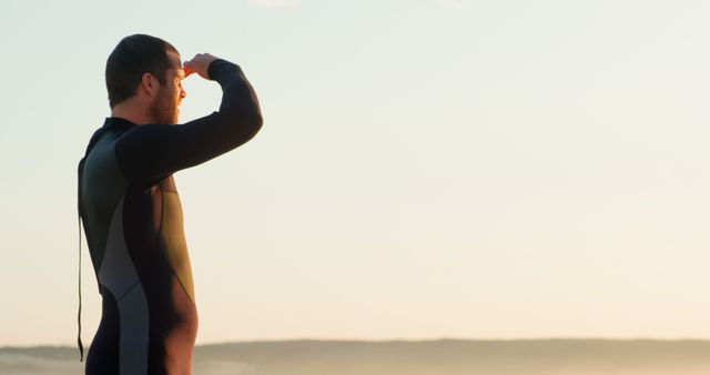 Surfer Looking at Ocean Horizon in Wetsuit during Sunrise - Download Free Stock Images Pikwizard.com