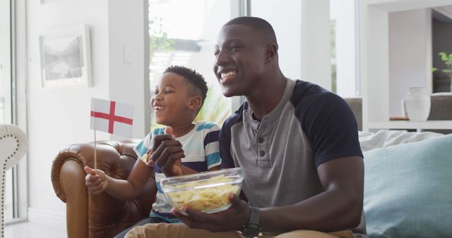 Father and Son Watching Football Holding England Flag in Living Room - Download Free Stock Images Pikwizard.com