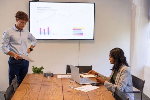 Diverse team analyzing digital adoption charts and reports during collaborative boardroom meeting