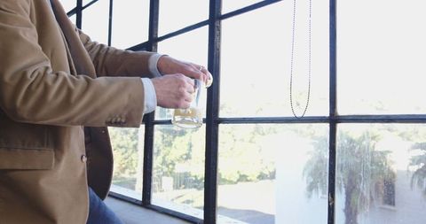 Businessman enjoying beer break by large window in stylish office