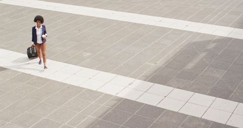 Businesswoman Walking with Coffee and Luggage in Urban Setting