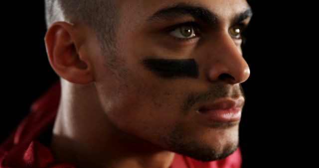 Close-up of football player with eye black, showing strong determination and focus. Ideal for sports-related advertisements, motivational posters, athlete profiles, and team spirit promotions.