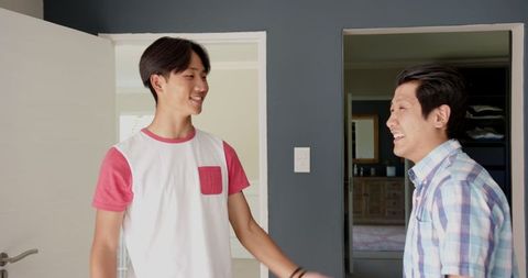 Asian Father and Teenage Son Sharing Special Moment at Home Entrance