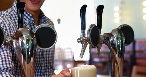 Bartender Pouring Fresh Draft Beer in Lively Bar Atmosphere