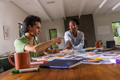 Indian man and african american woman collaborating on creative project at home workspace